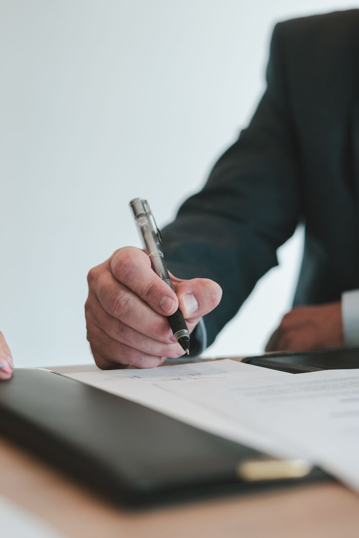 The Art of Drawing Readers In: Your attractive post title goes here A businessman in a suit signing a contract in an office setting, emphasizing professional context.