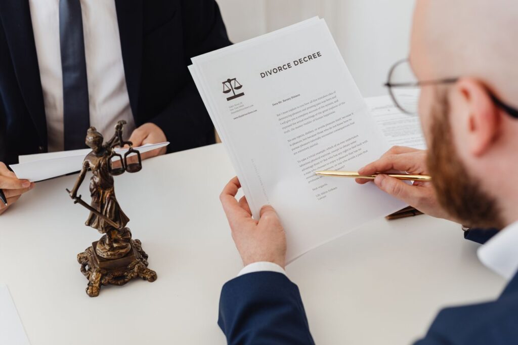 Two professionals examining a divorce decree with a Lady Justice statue nearby.